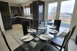 a dining table with wine glasses on it in a kitchen at Tides Reach - 3 Bedroom Holiday Home - Llanreath in Pembrokeshire