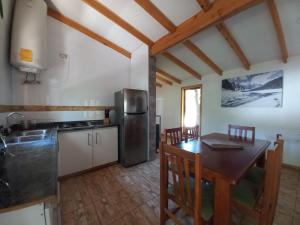 cocina con mesa y nevera de acero inoxidable en Cabañas Golem - Con Piscina, en Guangualí