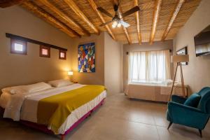 um quarto com uma cama, uma ventoinha de tecto e uma cadeira em Villa del Cielo em Tilcara