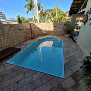 a blue swimming pool in a yard with a brick wall at Pousada das Pedras in Itacuruçá +36 photos