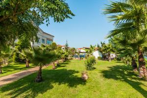 a lawn with palm trees in front of a house at Tresor Sousouras in Hanioti