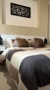 1 dormitorio con 1 cama grande con almohadas marrones en Tiwaline Tarsime App D, en Sidi Ifni