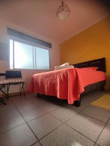 a bedroom with a bed with a red blanket on it at Aji Verde Hostel in La Serena