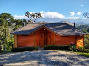 a wooden cabin with a mountain in the background at Pousada Mirante do Céu in Visconde De Maua