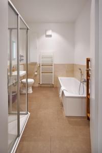 ein Badezimmer mit einer Badewanne, einem WC und einem Waschbecken in der Unterkunft Ferienwohnung Sicado Loft in Aschau im Chiemgau