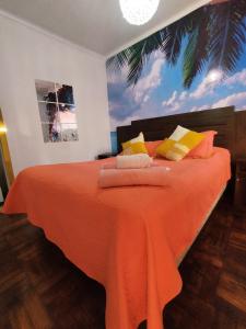 een slaapkamer met een bed met een oranje deken bij Aji Verde Hostel in La Serena