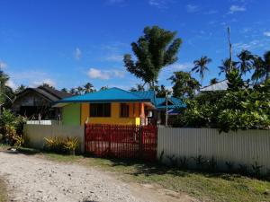 a house with a red fence next to a dirt road at Bundal Riverside Room#1 in Itaytay