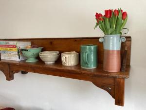 Un estante con un jarrón de flores y tazones. en Six on Castle, en Tiverton