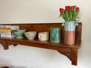 a shelf with a vase of flowers and bowls on it at Six on Castle in Tiverton