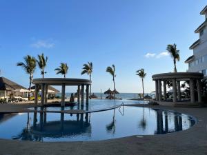 a swimming pool with palm trees and a beach at a pie de playa con hermosa vista by G P S rentas in Mazatlán