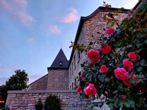 a brick building with pink roses and a church at Les Suites de Petit Bomal in Durbuy