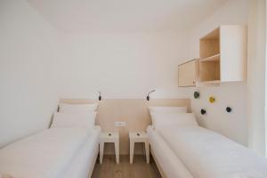 two beds in a room with white walls and wooden floors at stella alpina in Dobbiaco