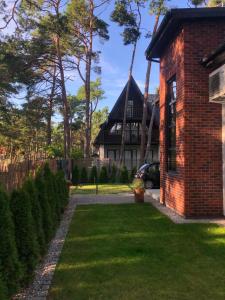 a brick house with a yard with grass and trees at Villa Ohana in Pobierowo 300 m from the beach in Pobierowo