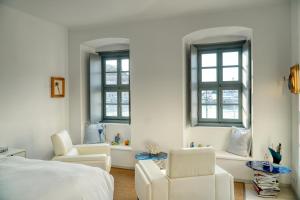 um quarto com 2 cadeiras, uma cama e janelas em MyCrown Suite, Luxurious apartment with sea view located at the port of Hydra em Hidra