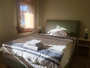 a bedroom with a bed with white sheets and a window at Teos Lodge in Siğacık