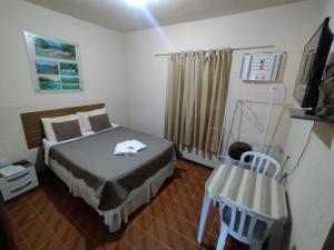 a small bedroom with a bed and a chair at Vale do Pontal Angra Suites in Angra dos Reis