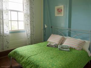a bedroom with a green bed with two pillows and a window at Hospedaria Os Memorialistas - Paranapiacaba in Paranapiacaba