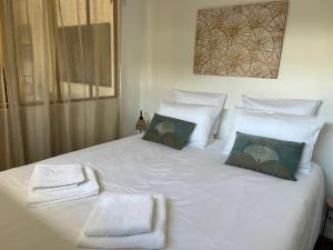 a large white bed with two towels on it at Lodge LE CABANON accès direct plage ! in La Turballe