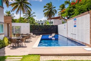 a swimming pool in a backyard with a table and chairs at Solar Porto Rico in Porto De Galinhas