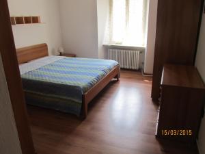 a small bedroom with a bed and a wooden floor at Appartamento Alessio in Ledro