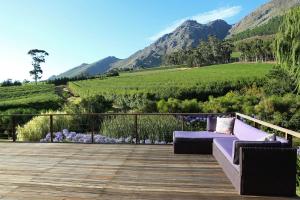 a purple couch on a deck with a view of a mountain at VILLA DE LUC Ultimate Country Privacy in Franschhoek