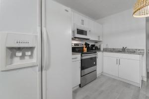 uma cozinha com armários brancos e um frigorífico em Splendid Location Apt close to Brickell & Marlins Park em Miami