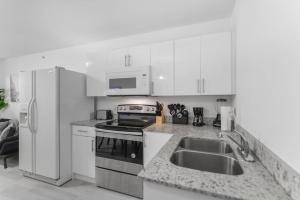 uma cozinha branca com um lavatório e um frigorífico em Splendid Location Apt close to Brickell & Marlins Park em Miami