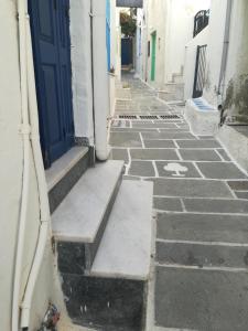 an empty alley with a blue door and steps at Mama's House in Ios Chora