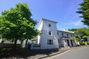 a white house with a tree on a street at TorquayTownhouse with Hot Tub 200m from Beach - Free WiFi Sky Glass in Torquay