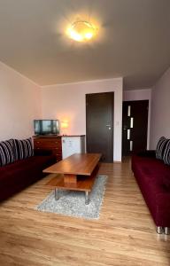 a living room with a red couch and a wooden table at Pokoje Gościnne - HESJOK in Ustronie Morskie