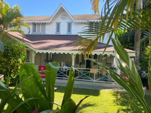 a white house with a porch with a fence at Caribbean Villa Los Lobos Ballenas Beach in Las Terrenas