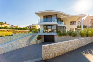 a house with a stone retaining wall and a stone fence at Villa Piano Residences in Vantačići