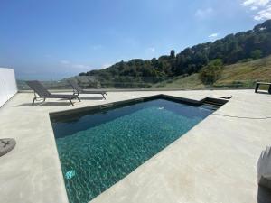 - une piscine avec 2 chaises assises à côté dans l'établissement Ece Golden Villa Amazing 4 bedroom vila with pool, à Alella