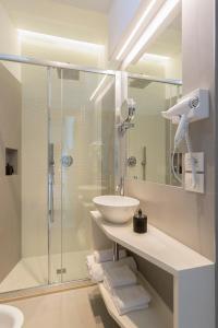 a white bathroom with a sink and a shower at Hotel Commodore in Riccione