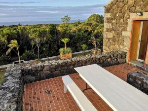 a stone building with a bench on a patio at Retiro dos Bons Sinais in São Roque do Pico