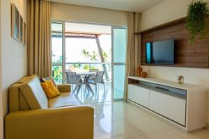 a living room with a television and a couch and a table at Solar Porto Rico in Porto De Galinhas