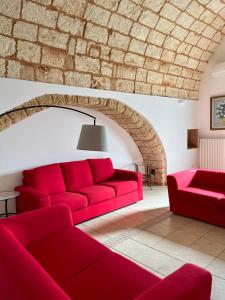 un divano rosso in un soggiorno con muro di mattoni di Il Frantoio a Depressa