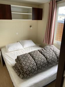 - un lit dans une chambre avec fenêtre dans l'établissement Camping le Clos Savoye, à Biville-sur-Mer