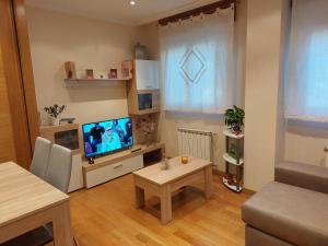 een woonkamer met een televisie en een tafel bij Apartamento Vieiro con plaza garaje gratis in Santiago de Compostela