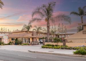 a rendering of the exterior of a resort with palm trees at Anaheim Islander Inn and suites near Park and Convention center in Anaheim