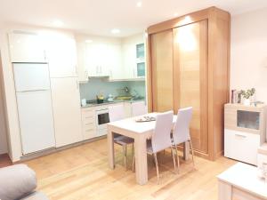 a kitchen with white cabinets and a table and chairs at Apartamento Vieiro con plaza garaje gratis in Santiago de Compostela +5 photos