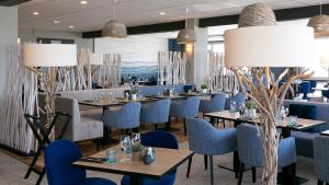 a dining room with tables and blue chairs at Logis Hôtel Le Calluna Restaurant La Flottille in Préfailles