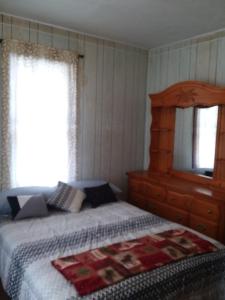 a bedroom with a bed with a wooden headboard and a window at Hemlock House in Ironwood
