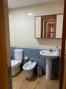 a bathroom with two sinks and a toilet and a mirror at Santiaguiño in Padrón