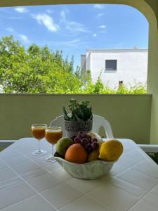 a bowl of fruit on a table with two wine glasses at Pomerino Apartmans in Pomer
