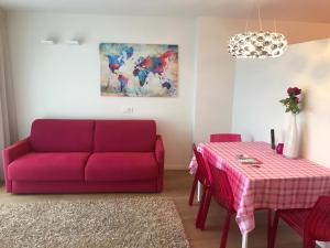 a living room with a red couch and a table at Casa con vista Sciliar centro paese PINK con parcheggio privato in Völs am Schlern