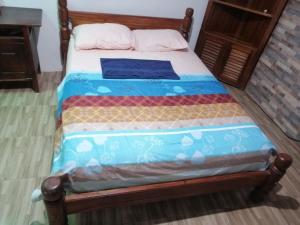 ein Bett mit einem Holzrahmen und einer blauen Decke in der Unterkunft APARTA-Refugio El Retiro Verde in Leticia