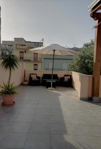 un patio con sombrilla y sofás en un edificio en b & b Jasmine, en Santa Teresa di Riva