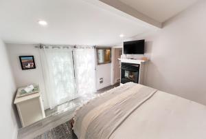 a white bedroom with a bed and a fireplace at Inn at Cook Street in Provincetown