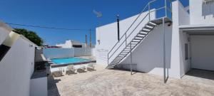 a white house with a staircase and a swimming pool at Casa Las Marismas in Barbate